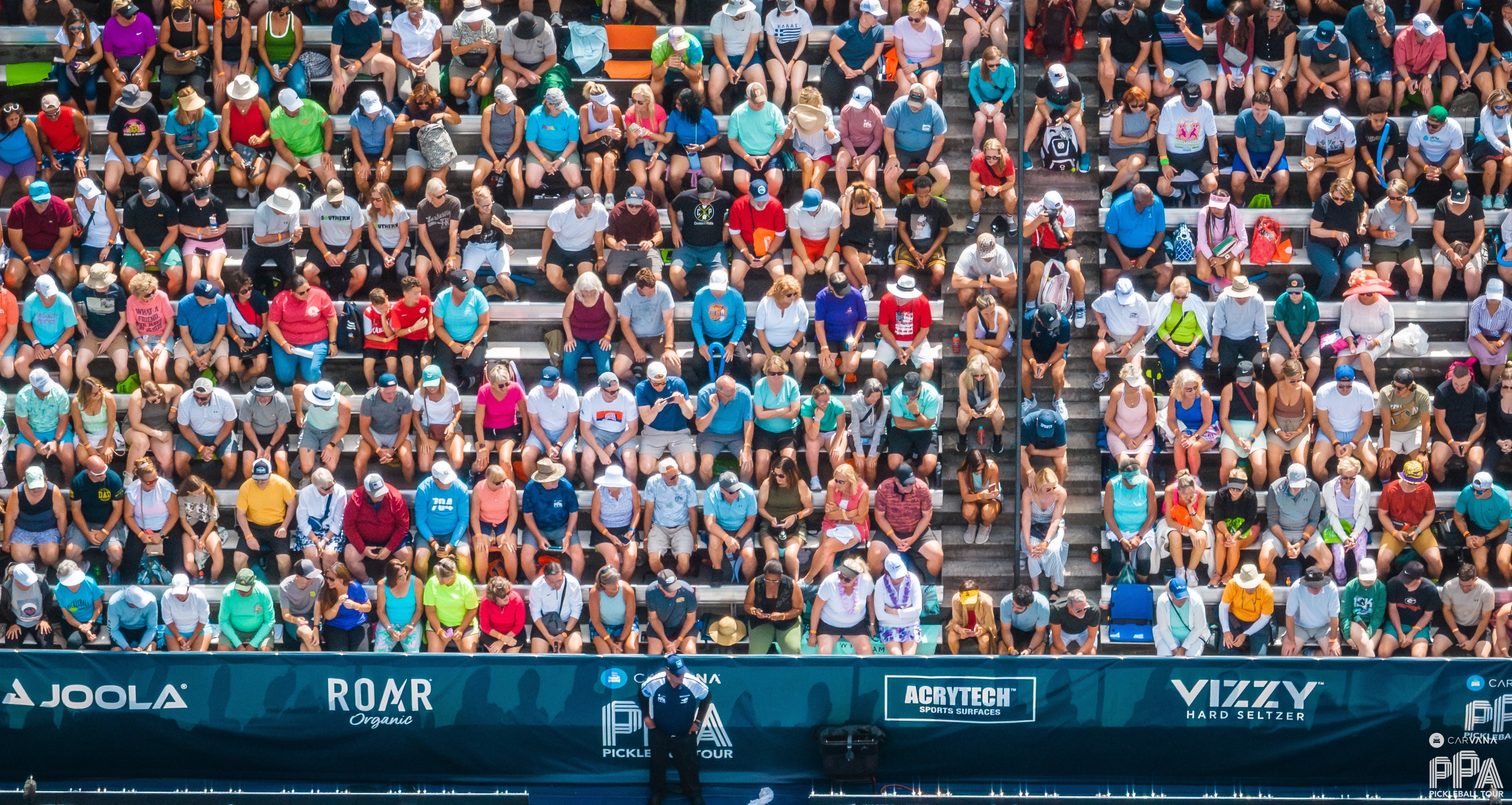 A packed crowd of pro pickleball fans observe a match