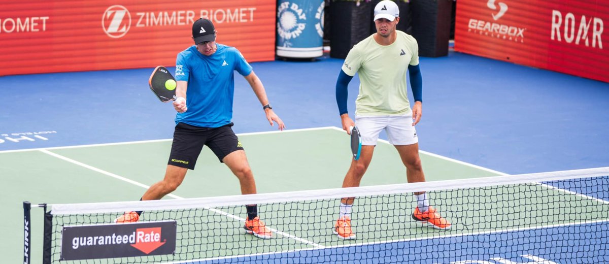Collin Johns hits a pickleball next to brother Ben Johns.