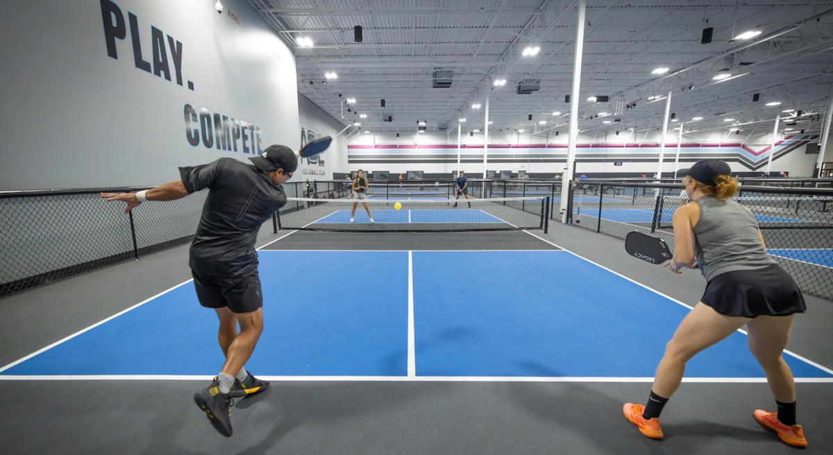 A pickleball player serves to start a point.