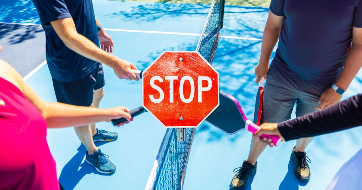 A stop sign in the middle of pickleball players paddle tapping