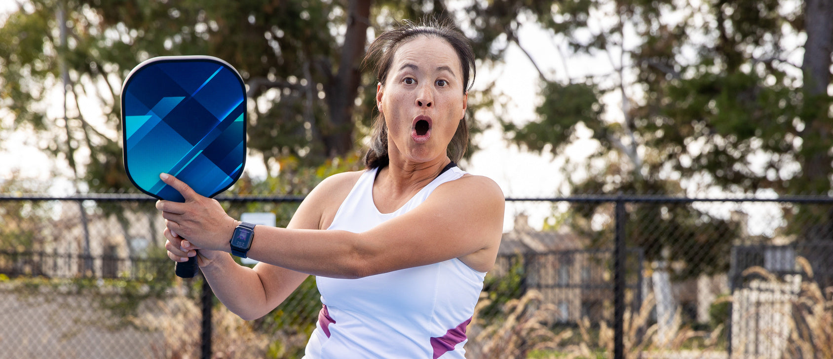 A beginner pickleball player with an inexpensive pickleball paddle held out
