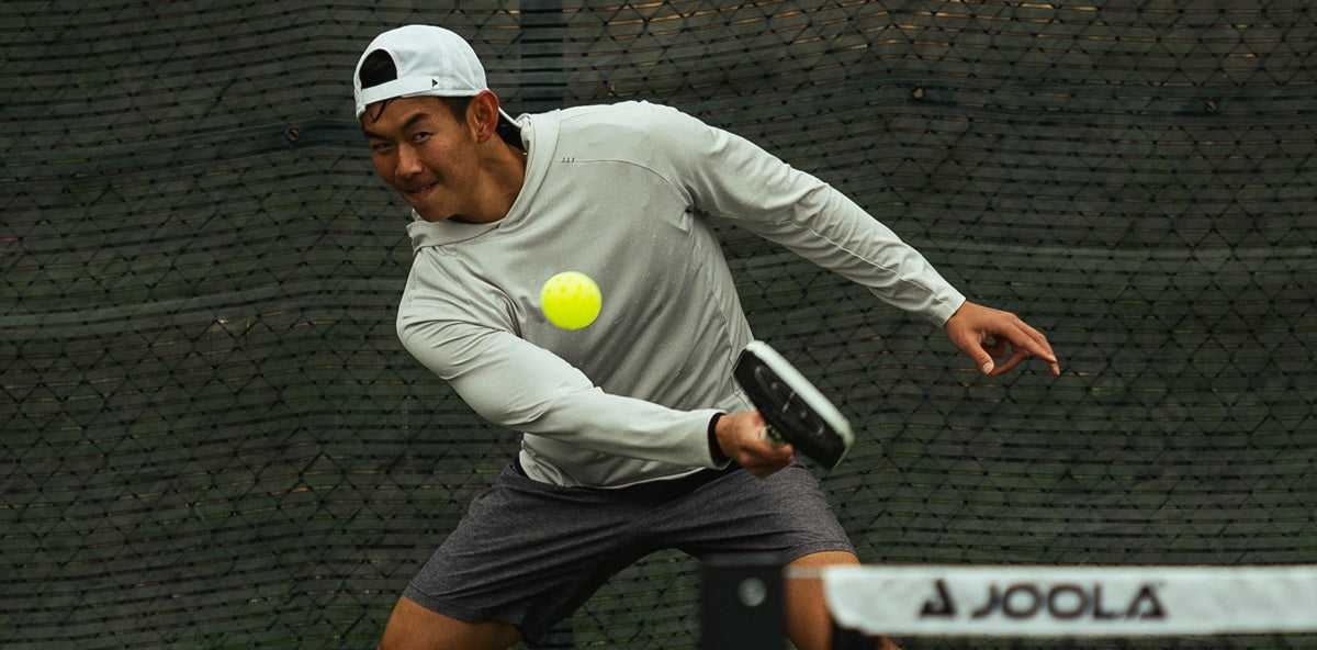 A pickleball player strategically applies spin to a shot during a match.