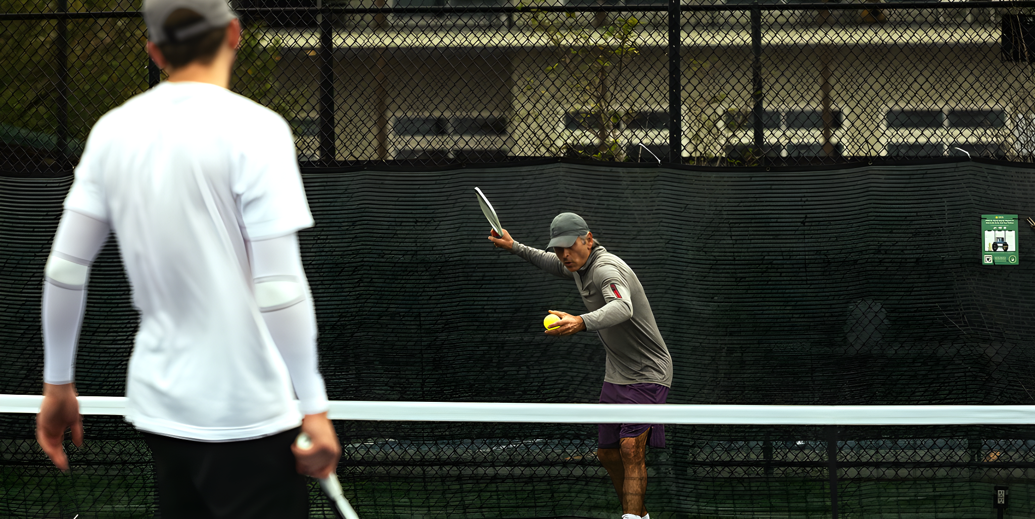 A pickleball player practicing his serve with partners of similar or lesser skill
