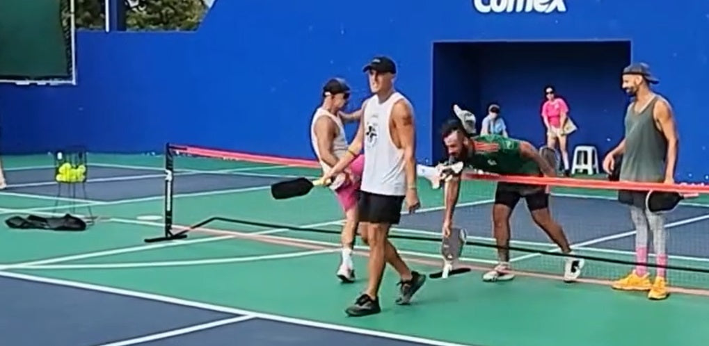 An upset, violent player kicks another on the pickleball court