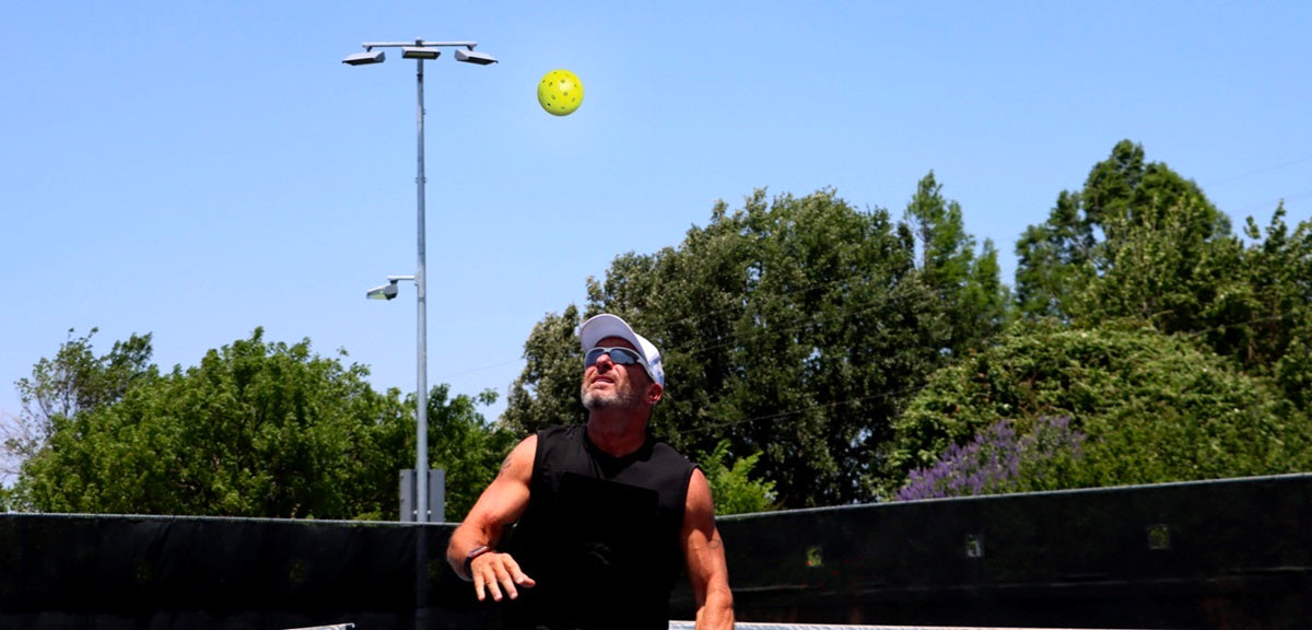 Good lob technique demonstrated by this pickleball going over a man's head on the court