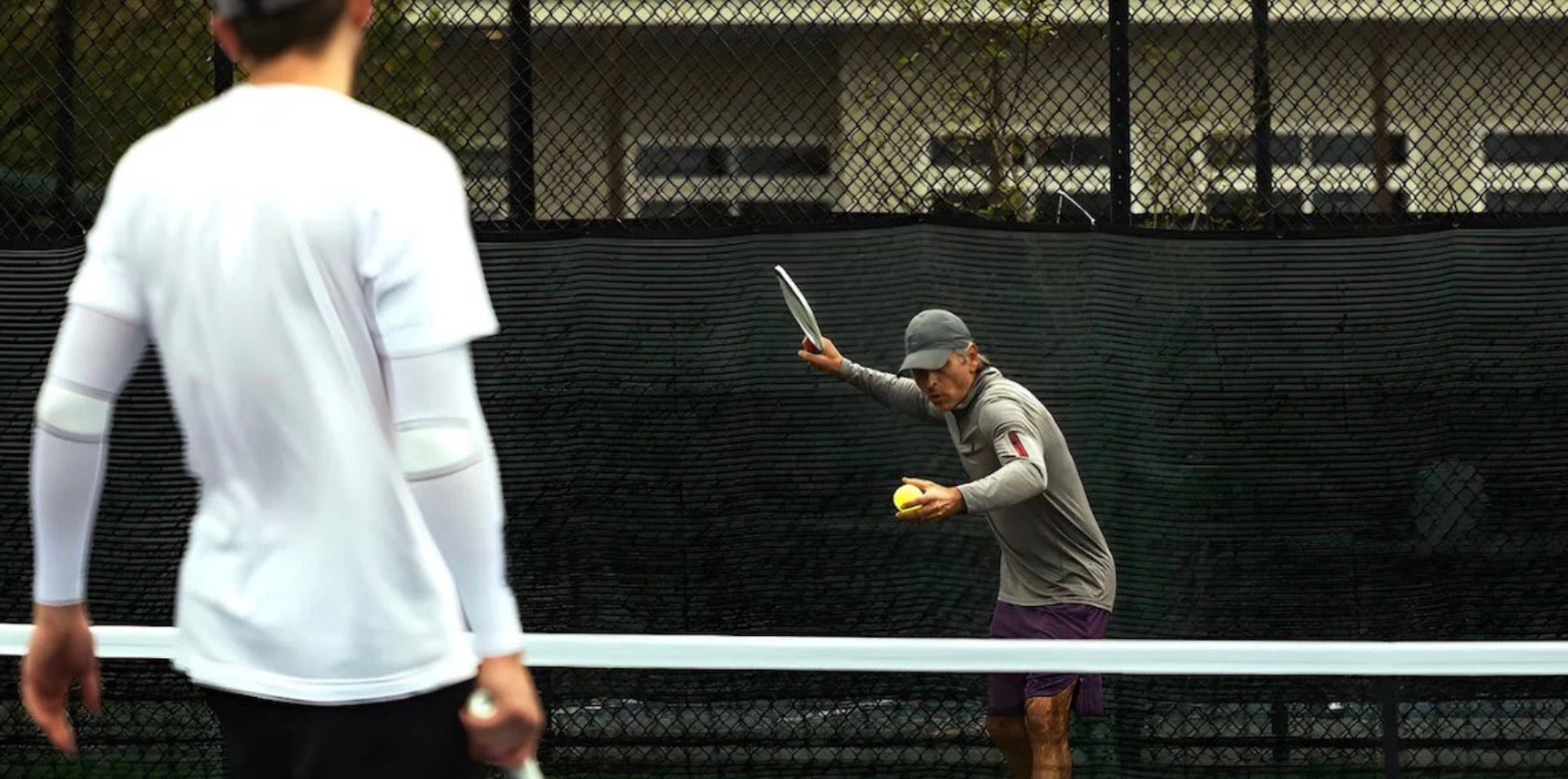 An amateur pickleball player serves the ball.