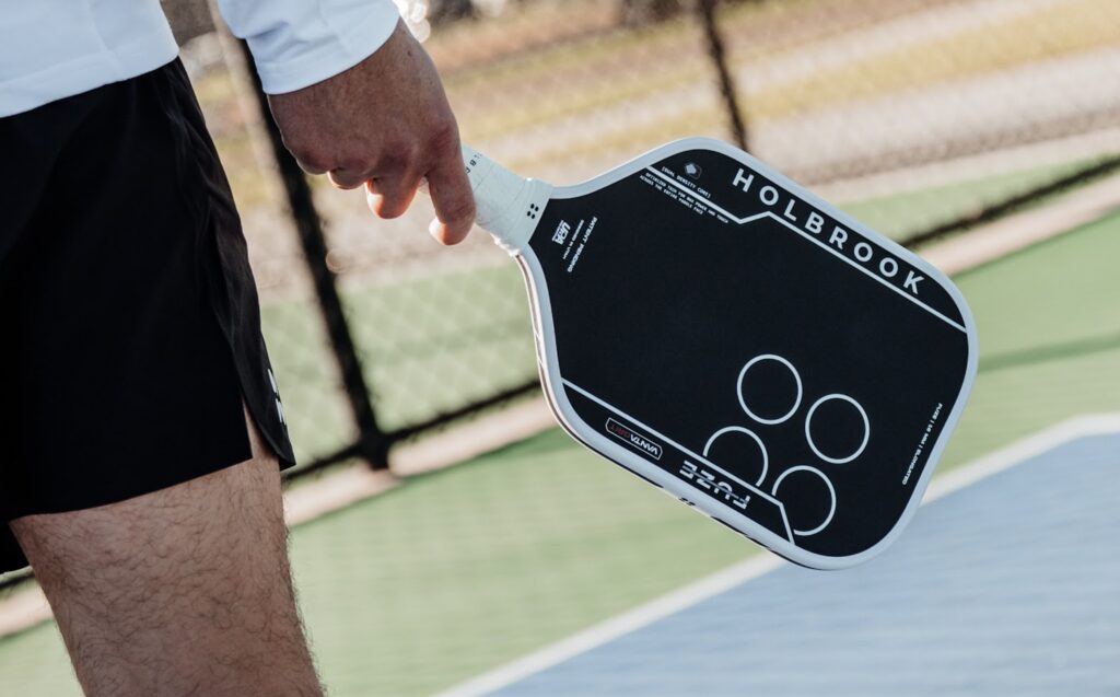 A player holds the new Holbrook Fuze VantaGrit pickleball paddle.